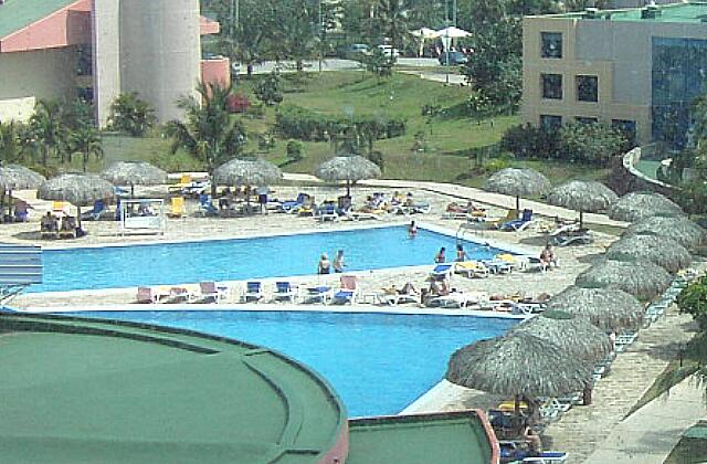 Cuba Varadero Mercure Playa De Oro Une belle piscine divisé en deux sections. Des chaises longues recouvertes de tissus, des parasols autours de la piscine, une grande terrasse.